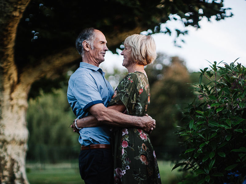 A couple dating after 50, smiling and hugging while looking into each other's eyes.