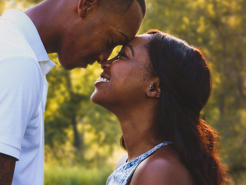 A couple laughing as they lean their foreheads together because they've found the one.