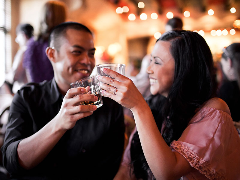 A guy who just asked "What your sign?" having a conversation with a woman at the bar.