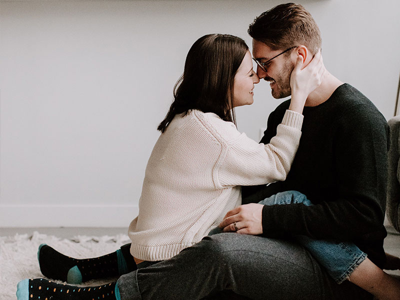 A couple who just finished asking each other 36 questions, sitting on the floor together and cuddling and laughing.