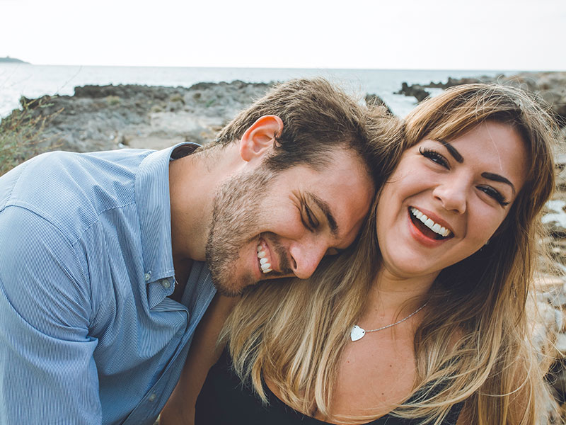A woman who learned about the body language of men, laughing with her boyfriend as he leans on her.