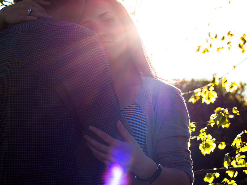 A woman who learned how to make up after a fight, hugging her boyfriend in the sun and reflecting.