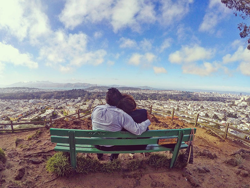 A couple who took these mature dating tips, sitting on a bench and looking at the city view.