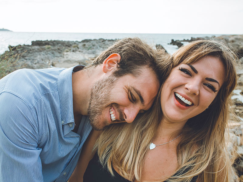 A woman wondering "Do I like him?" as she laughs while a man she's into leans on her and laughs along with her.
