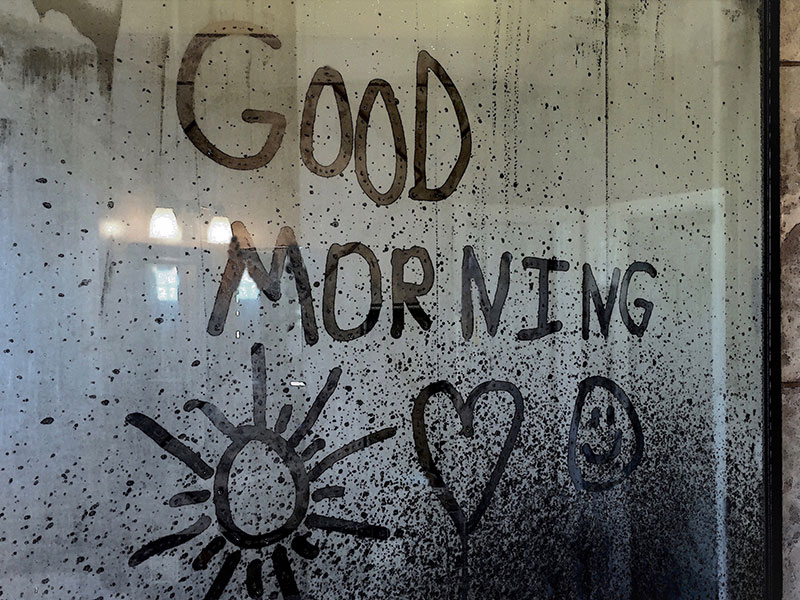 A message written on a rainy window that says good morning from a man who learned how to be romantic.