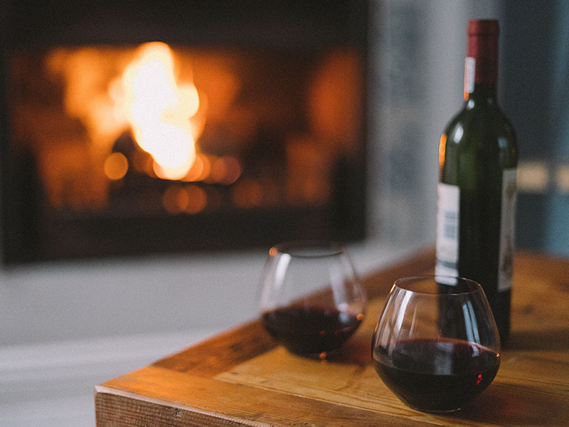A fireplace and wine and two glasses sitting out on a couple's third date.