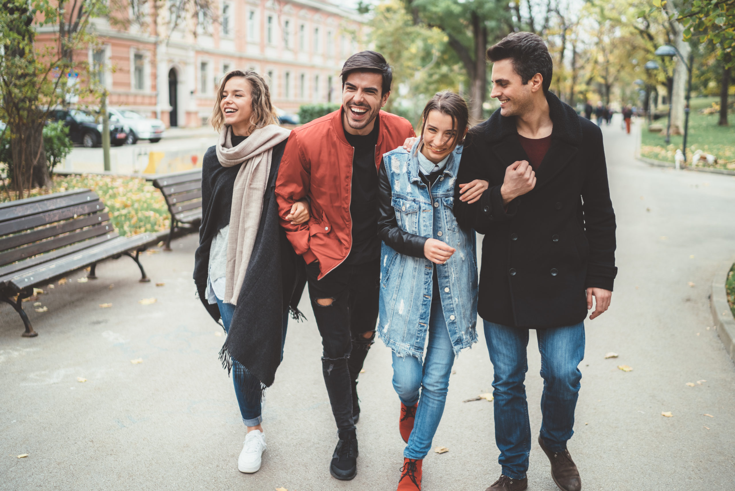 Two happy couples walking down the street together and laughing while trying out some of the best double date ideas.