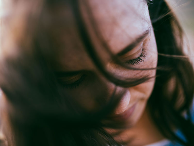 A woman who's a victim of chronic stonewalling, looking down and thinking while obviously upset.