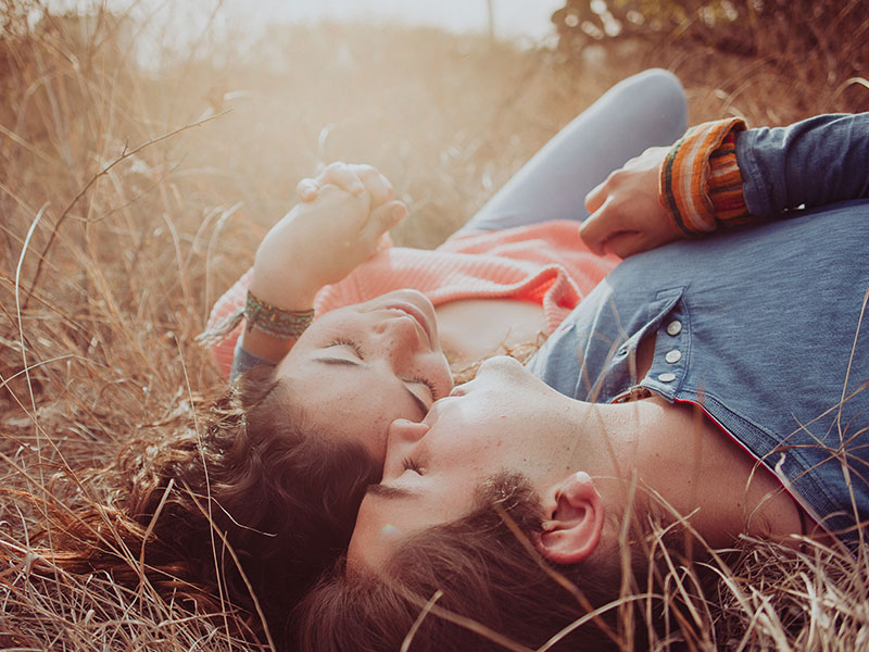 A couple with a strong emotional connection, in a field together talking and cuddling.