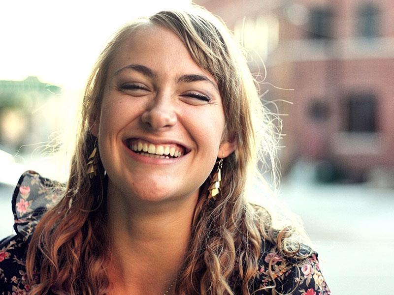 A woman who stopped saying I want to fall in love and embraced being single, laughing to herself on the street.