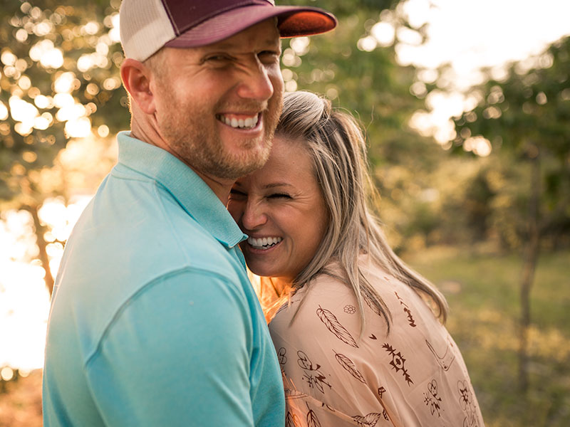 A happy couple where the woman maintains her independence laughing in the forest.