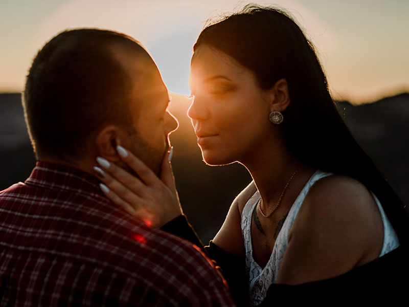 A couple who's showing signs of love, looking into each other's eyes intensely before kissing.