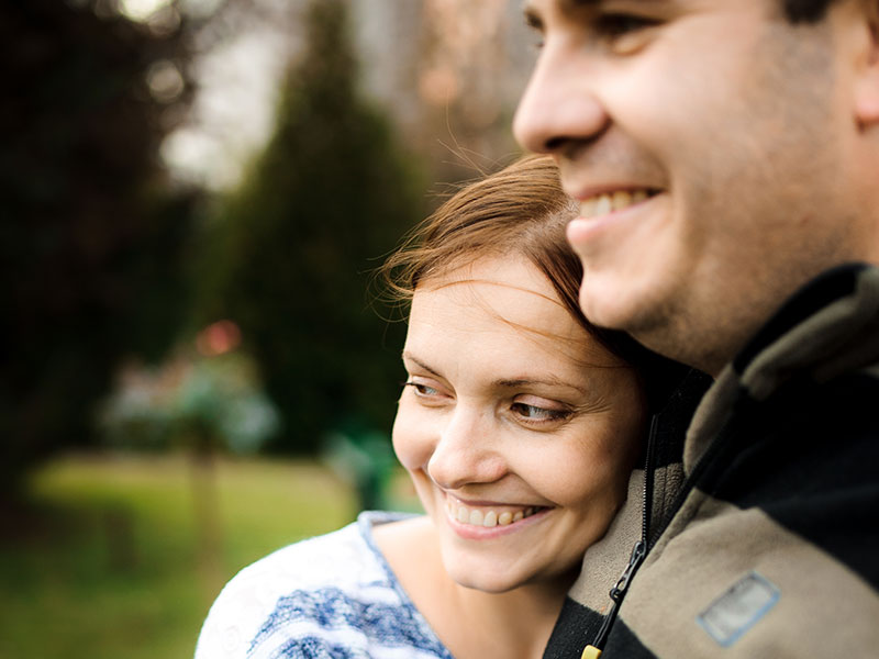 A couple in unconditional love, smiling and hugging outside.