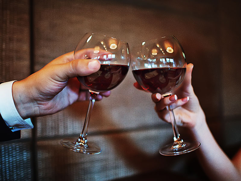 A couple about to have drunk sex cheersing their wine glasses.