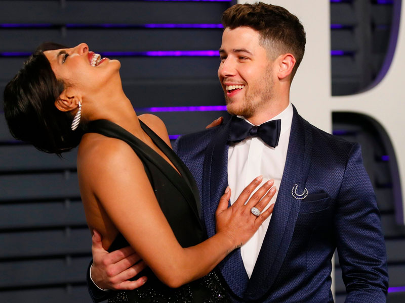 Nick Jonas and Priyanka Chopra, one example of an older woman dating younger men, laughing and hugging at a red carpet event.