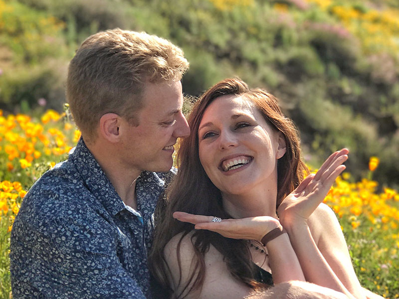 A woman who's potentially coming on too strong smiling up at her boyfriend in a field.