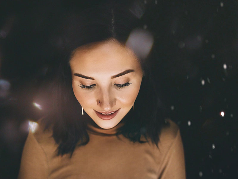 A woman who learned how to deal with rejecting, thinking and looking down with a smile in the twilight.