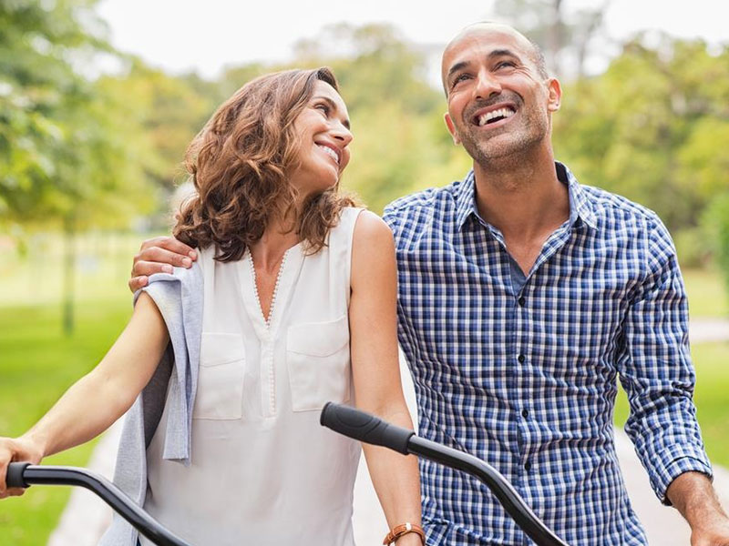 A couple dating over 40 laughing and smiling on their bikes together.