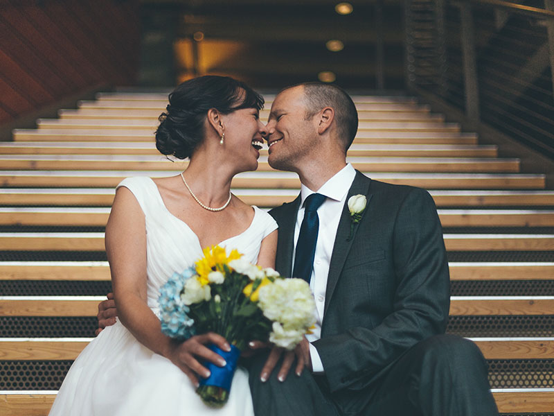 A couple who learned a thing or two from these true love quotes, sitting on the church steps on their wedding day touching noses and laughing together.