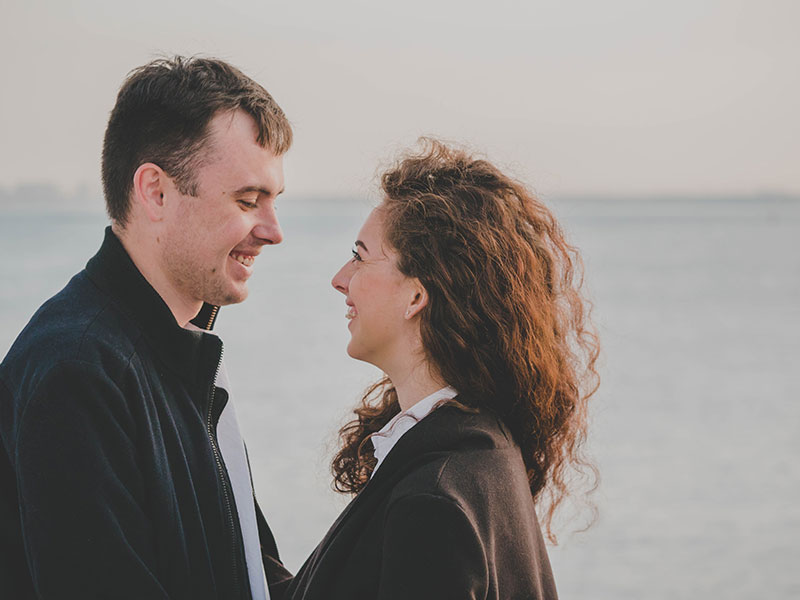 A guy using one of these flirty conversation starters looking at a woman on the beach and smiling.