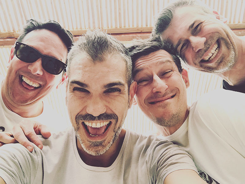 A group of guys who learned how to make friends in college laughing and taking a selfie together.