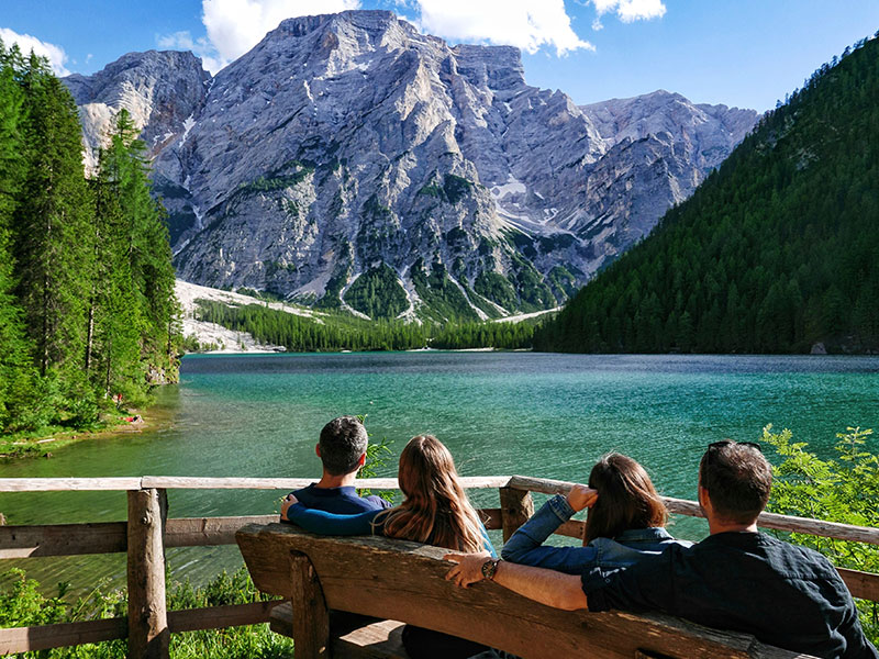Four people in a quad relationship hanging out on a bench in front of a beautiful lake.