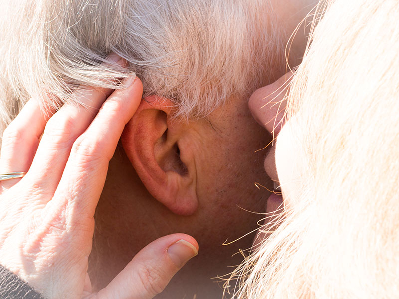 A woman whispering in her dates ear, after listening to some of these senior dating tips.