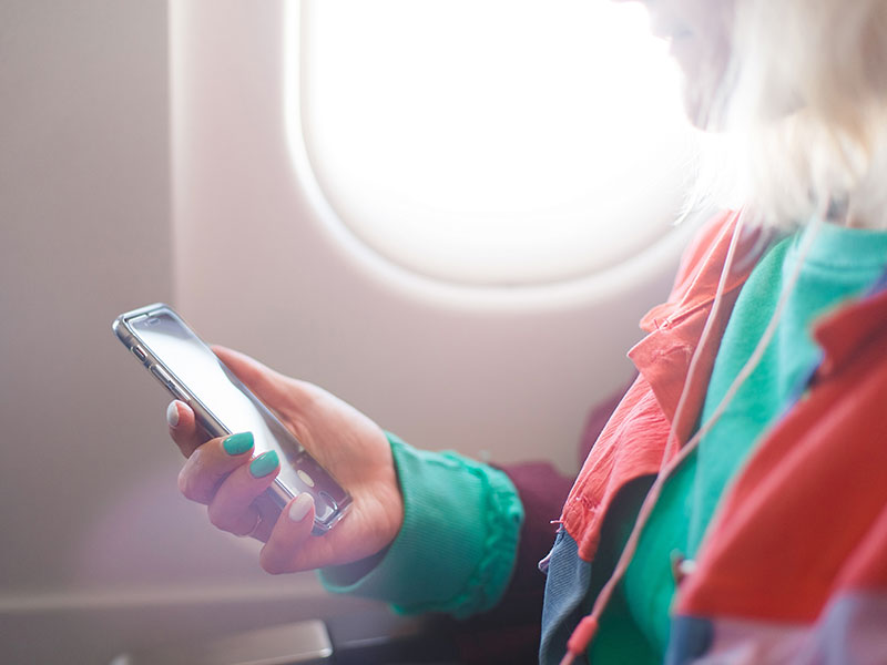 A girl listening to one of the best relationship podcasts on her phone while on a plane.