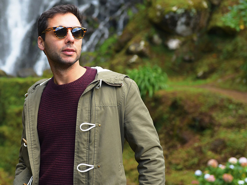 A guy standing outside looking cool in his sunglasses, who shows some of the signs of a player.