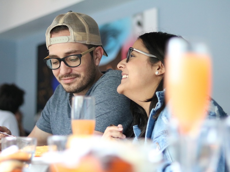 A couple laughing in a cafe with the guy giving off signs he's into you