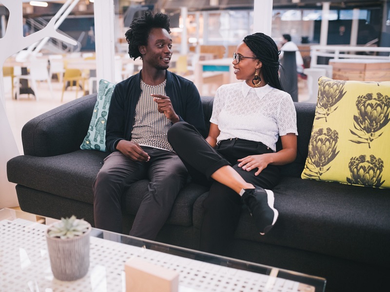 couple sitting on a safe in a cafe with her trying to read the male body language signs of attraction