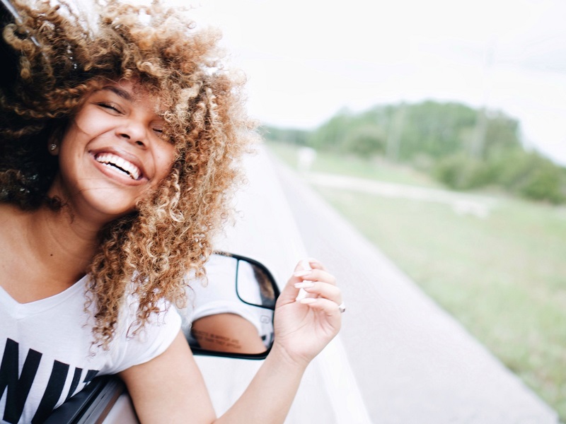 woman laughing out car window learning how to be more confident in yourself
