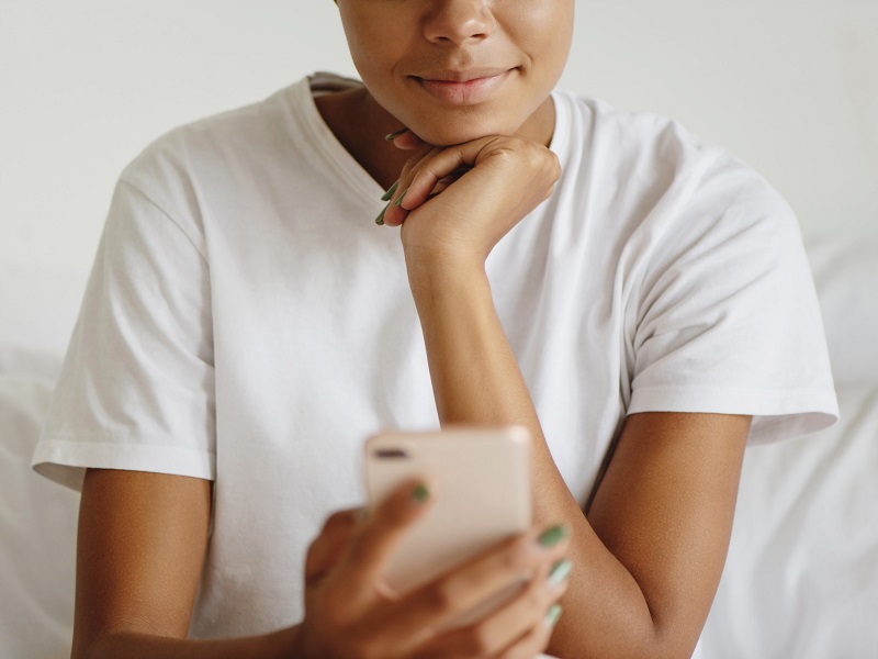 woman-smiling-at-her-phone-as-she-recieves-good-morning-text-messages