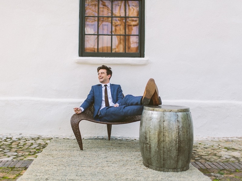 young businessman laughing on stool showing how to be a man