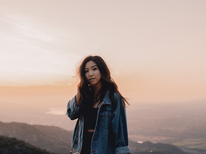 woman smiling on mountain side in front of sunrise