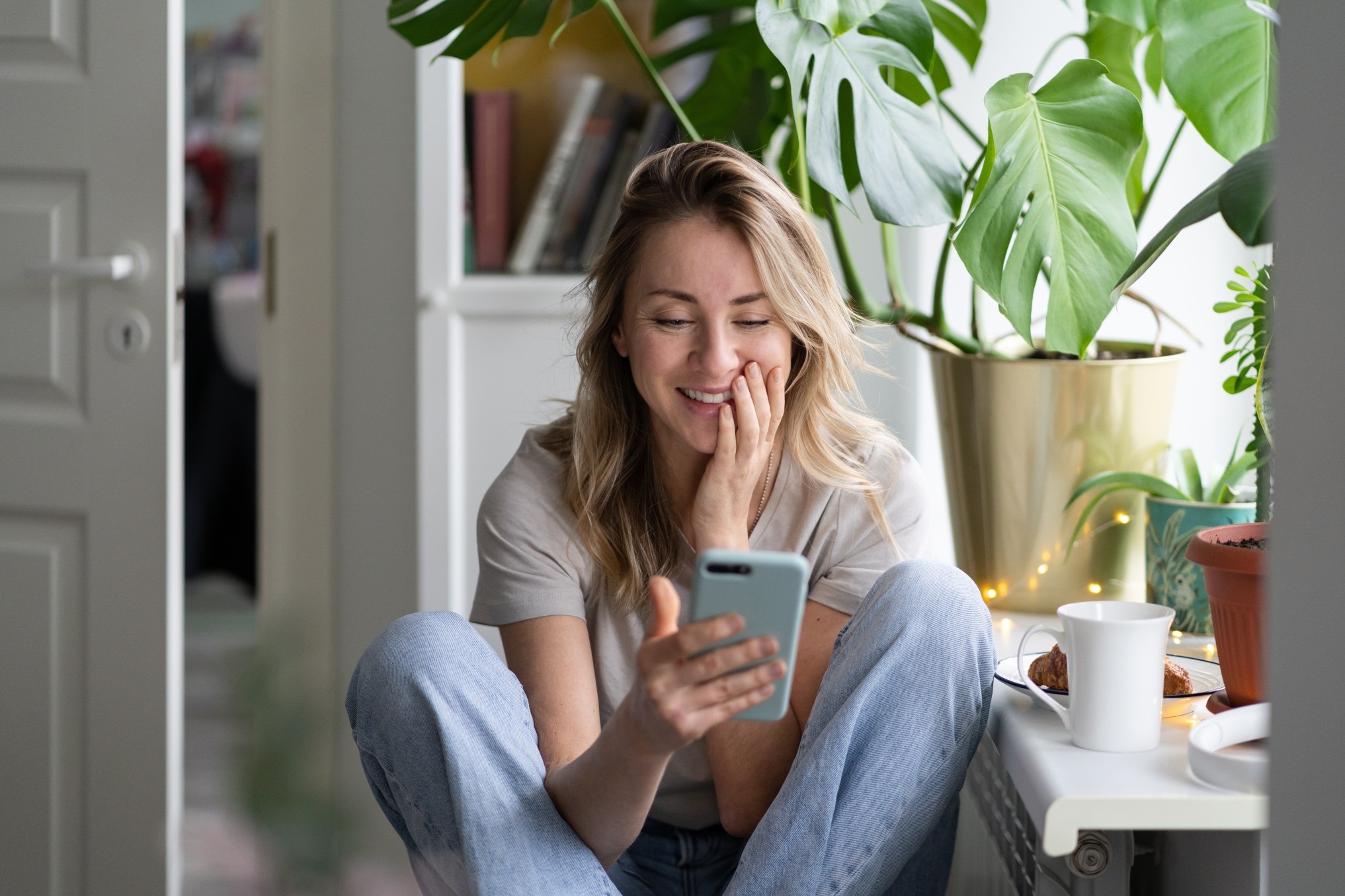 laughing woman holding mobile and video dating in kitchen