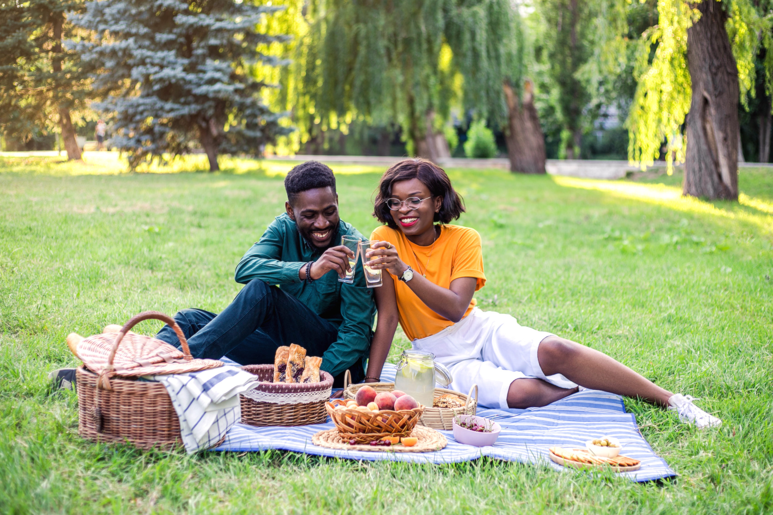 Young couple smiling together while having a picnic in the park as an easy first date idea.