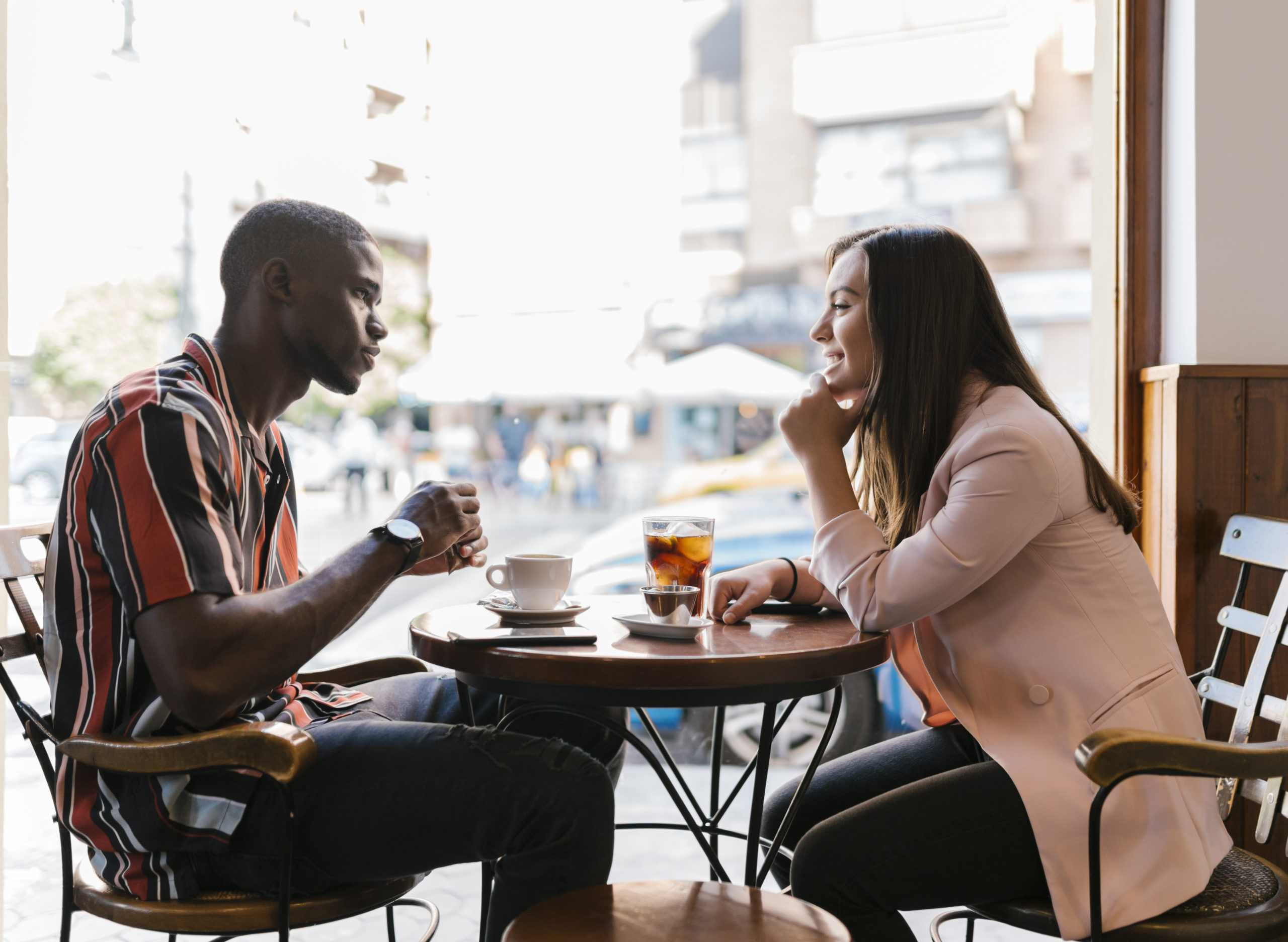 Happy couple on a first date in a coffee shop, smiling and talking.