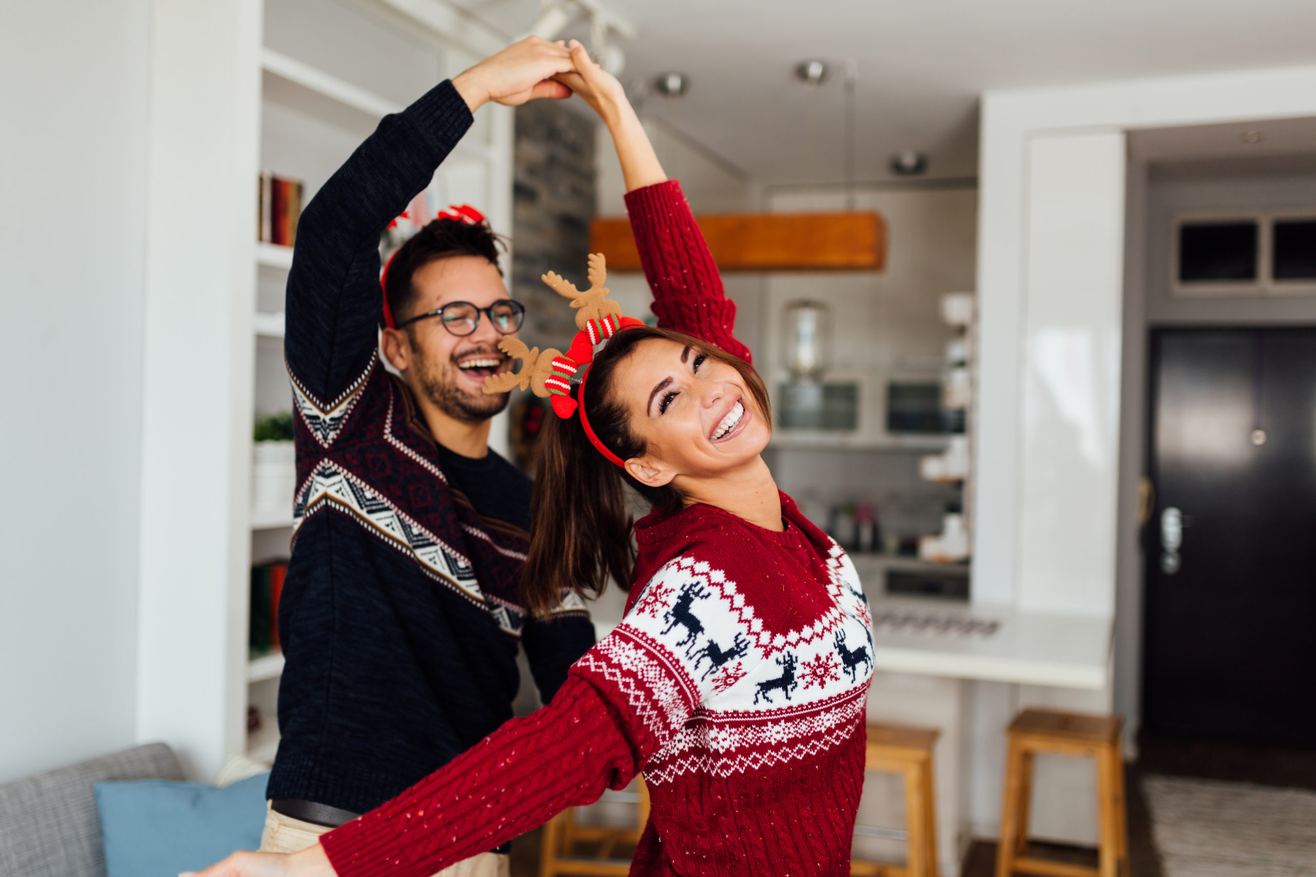 Happy couple smiling and dancing in Christmas setting while dating during the holidays.