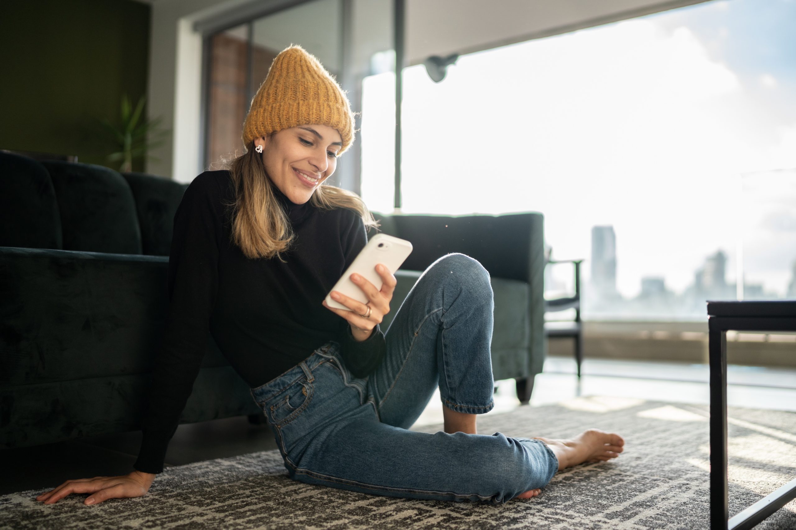 Smiling woman using smartphone at home during Dating Sunday.