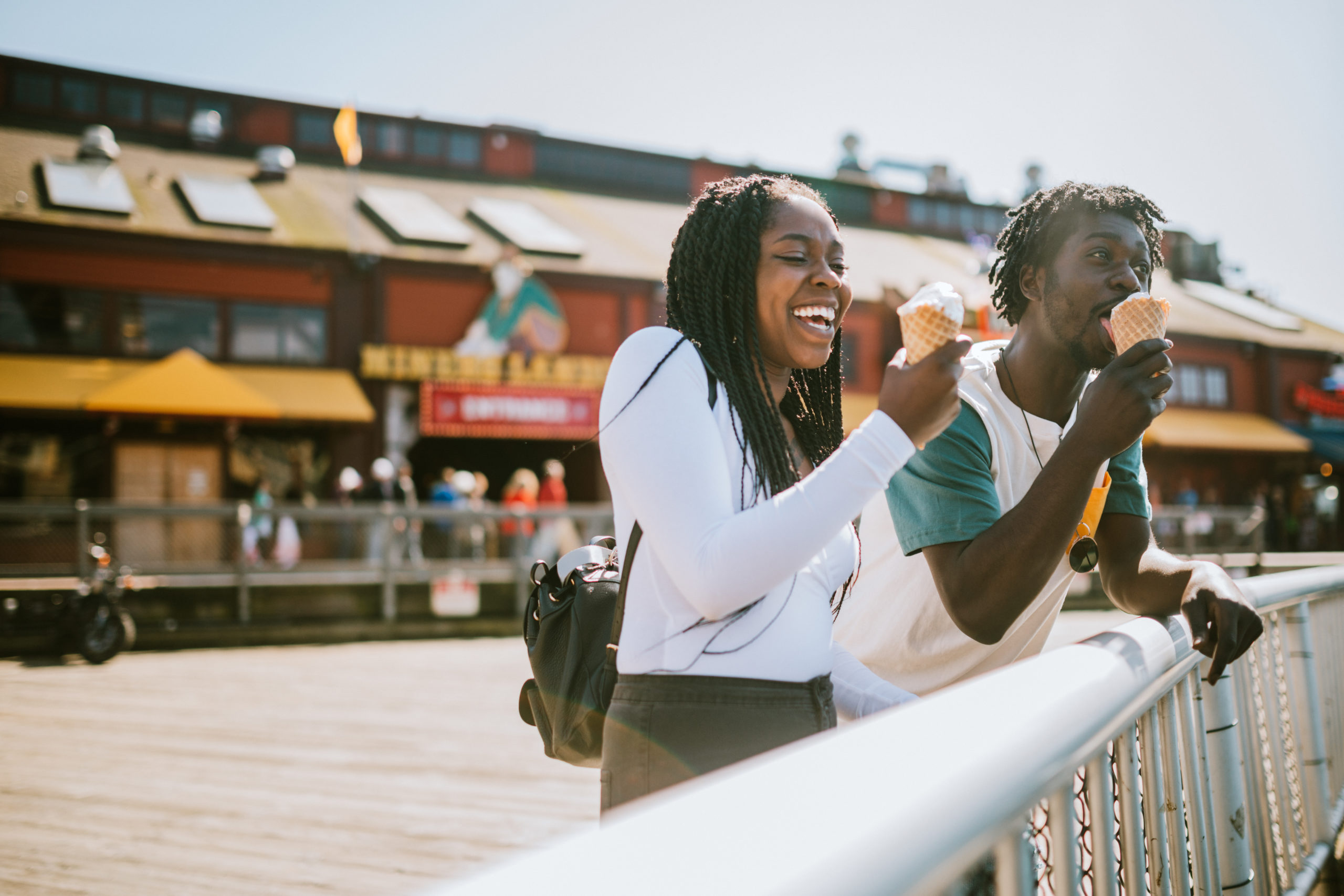 Young couple on a date eating ice cream while man is making woman laugh after thinking about what to say to a girl.